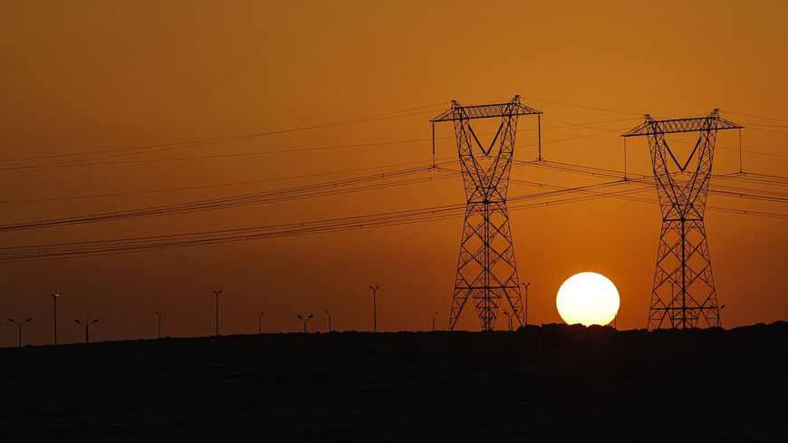 The sun sets behind high voltage transmission towers (electricity pylons) along a highway in El-Shorouk, a satellite city about 47 kilometers outside the city center of Cairo, on July 24, 2023. 